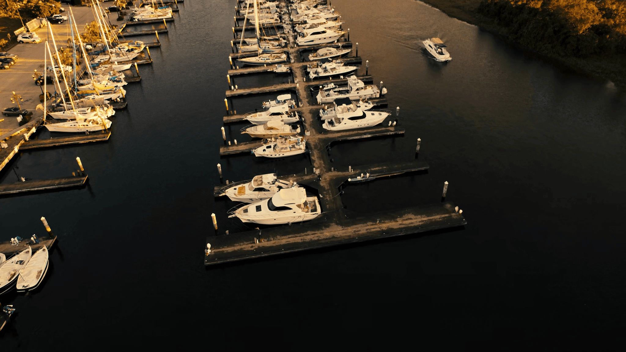 Aerial view of Anchorlight Marina at golden hour — four piers of berthed boats inside the seawall on Biscayne Bay